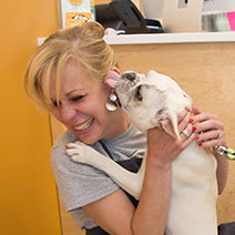 Woman holding a small white dog in an office setting